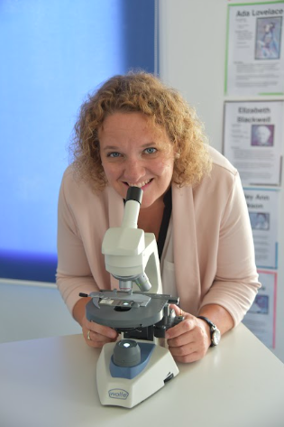 Kymberley smiling with a microscope